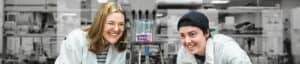 two students looks at Bunsen burner in a lab