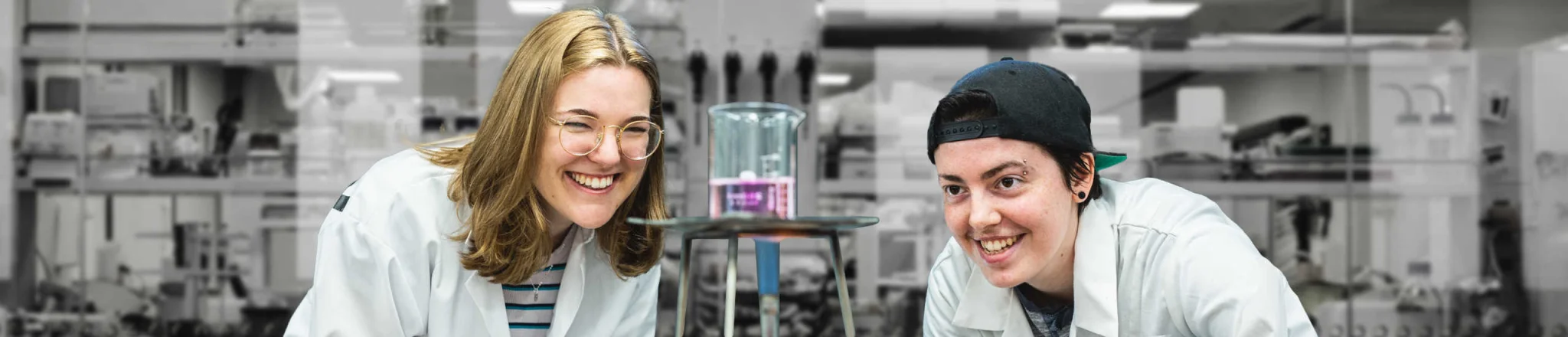 two students looks at Bunsen burner in a lab